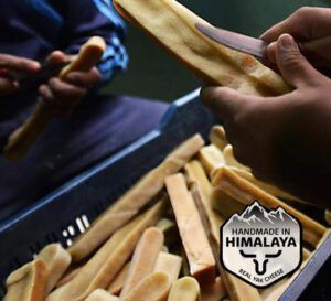 Dos personas haciendo barritas Churpi de leche de yak del Himalaya a mano. Premiar perro con Churpi